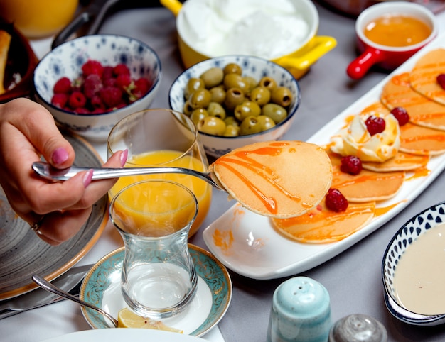 Pfannkuchen mit marmelade, oliven, einem glas saft und himbeeren ...