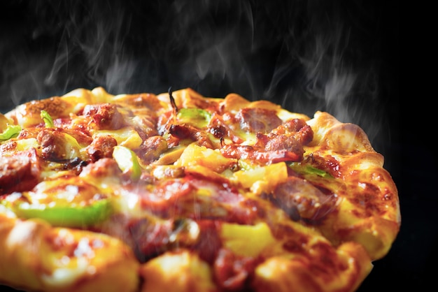 Pizza mit käse schinken speck und peperoni auf isolierten schwarzen hintergrund Premium Fotos