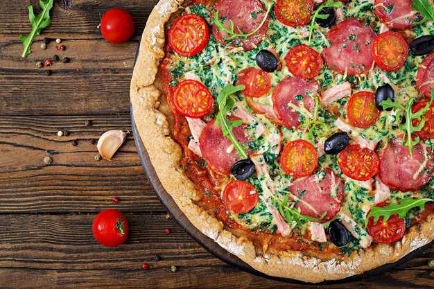 Pizza mit salami, tomaten, oliven und käse auf einem teig mit ...