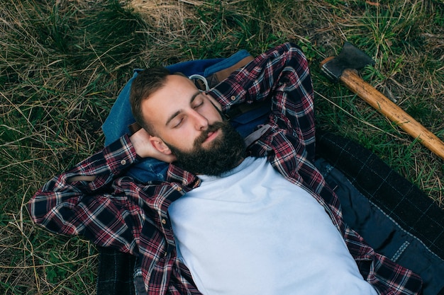 Portrat Brutal Bartigen Und Schnurrbartigen Holzfaller Hipster Zigeuner Mann Im Wald Mit Axt Mann Der Auf Dem Gras Liegt Und Traumt Premium Foto