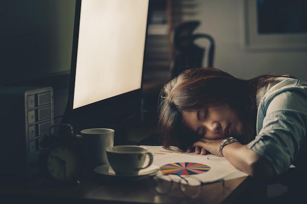 Porträt der asiatischen geschäftsfrau hart arbeiten und auf dem tisch schlafen Premium Fotos