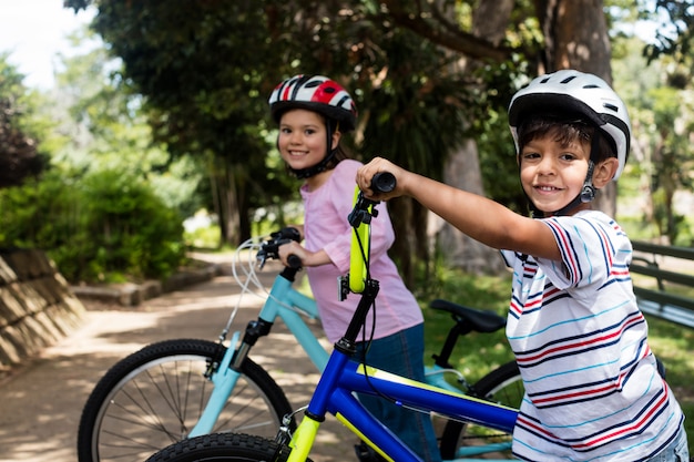 Porträt der lächelnden kinder, die mit fahrrad im park