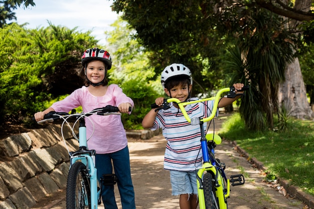 Porträt der lächelnden kinder, die mit fahrrad im park