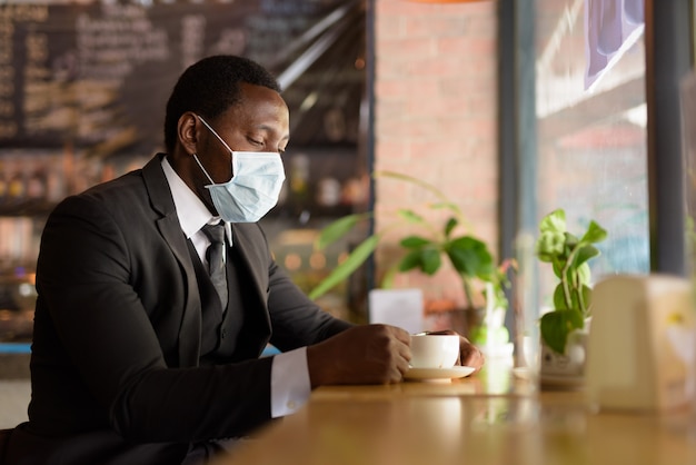 Portrat Des Afrikanischen Geschaftsmannes Der Maske Tragt Wahrend Kaffee Innerhalb Des Coffeeshops Als Die Neue Normalitat Trinkt Premium Foto