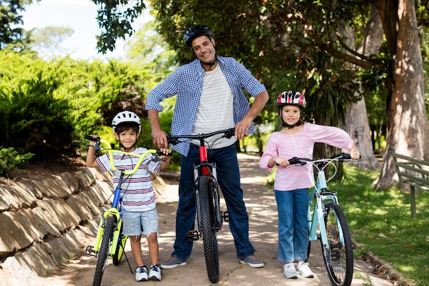 Porträt des vaters und der kinder, die mit dem fahrrad im