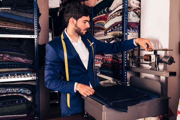 Porträt eines männlichen modedesigners, der die gewebewägemaschine in der werkstatt justiert Kostenlose Fotos