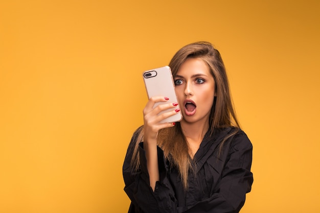 Porträt eines schönen mädchens mit einem wooku-telefon auf gelb Premium Fotos