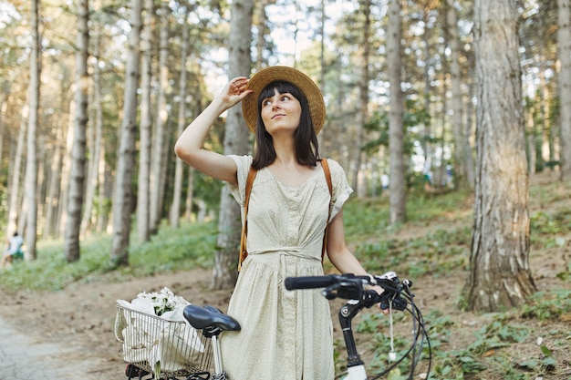 Porträt im freien des attraktiven jungen brunette in einem hut auf einem fahrrad. Kostenlose Fotos