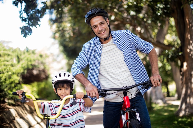 Porträt von vater und sohn, die mit fahrrad im park stehen