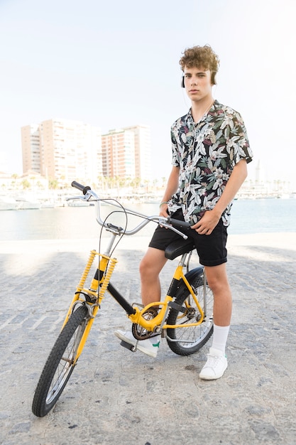 Portrait eines mannes mit gelbem fahrrad hörend musik