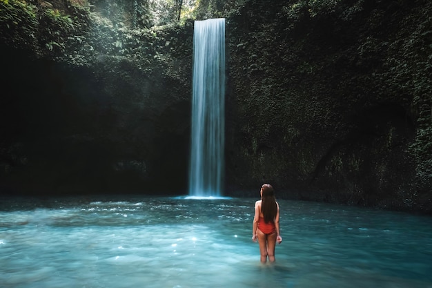Reisende junge frau mit tropischem regenwald in bali das leben am schönen tibumana-wasserfall genießend. Premium Fotos