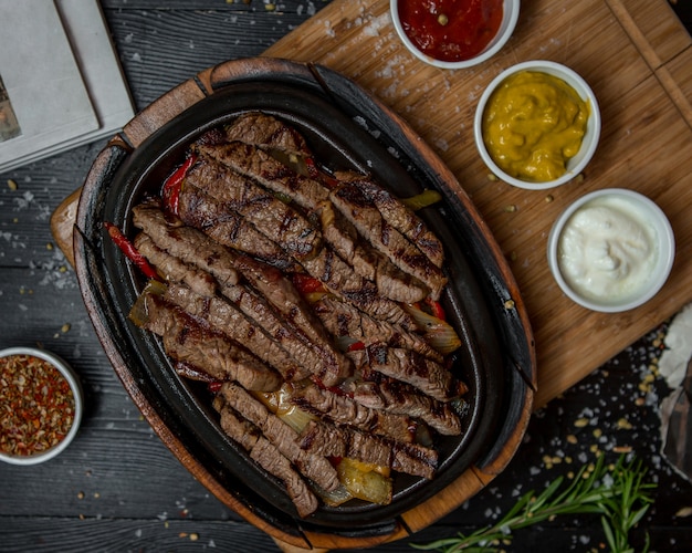 Rindfleisch fajitas mit drei arten von saucen auf einem holzbrett ...