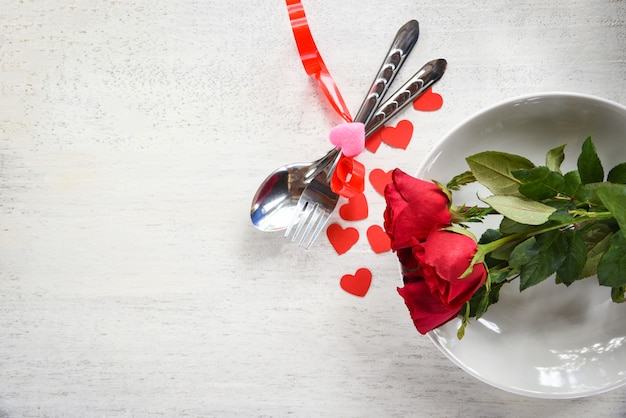 Romantisches liebeskonzept der valentinsgrußabendessen romantische tabelleneinstellung verziert mit gabellöffel rotem herzen und rosen auf platte Premium Fotos