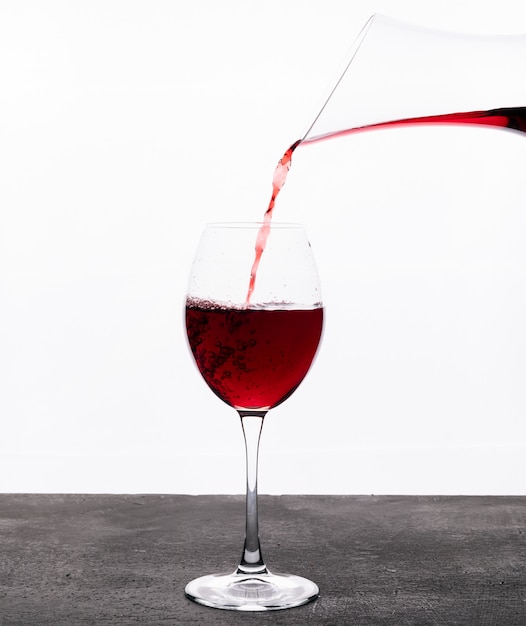 Rotwein der seitenansicht im glas auf weißer vertikal