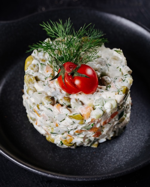 Russischer stolichni-salat mit tomate und dill auf die oberseite ...