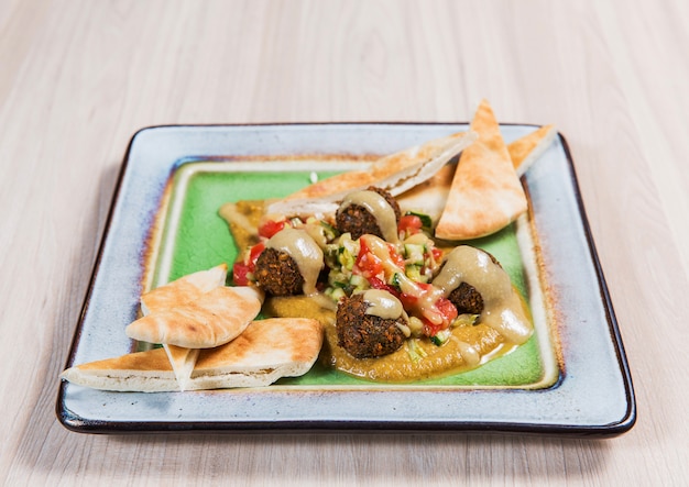 Salat mit fleisch und gemüse in der quadratischen platte auf hellem holztisch. gesundes essen Premium Fotos