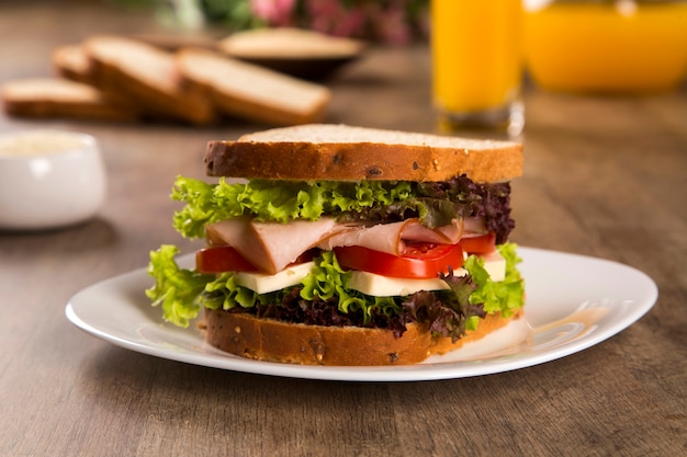 Sandwich auf einem weißen teller mit putenbrust, tomate, salat und käse ...