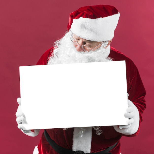 Santa claus, die leeres weißbuch in den händen hält Kostenlose Fotos