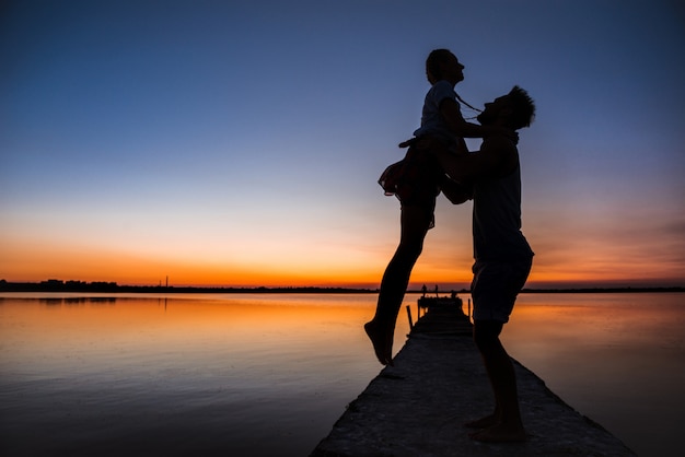 Schattenbilder des jungen schönen paares, das sich am sonnenaufgang