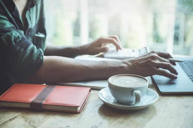 Schließen sie herauf kaffeetasse mit dem geschäftsmann, der laptop-computer und taschenrechner verwendet, um für rechnungsprüfungsbudget oder -finanzierung seiner firma zu calculatig. Premium Fotos