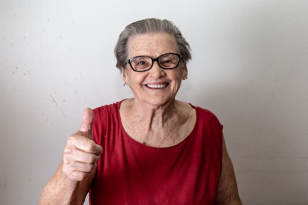 Schöne alte frau mit zwei stößen. netter kaukasischer senior, der zwei daumen oben auf weißem hintergrund zeigt. Premium Fotos