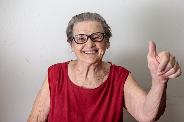 Schöne alte frau mit zwei stößen. netter kaukasischer senior, der zwei daumen oben auf weißem hintergrund zeigt. Premium Fotos