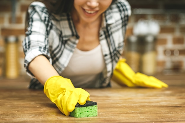 Schöne frau in der küche lächelt und wischt staub mit