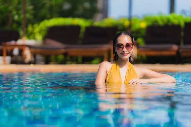 Schöne junge asiatische frauenfreizeit des porträts entspannen sich lächeln und glücklich um swimmingpool im hotelerholungsort Kostenlose Fotos