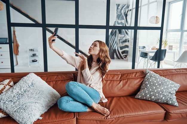 Schöne junge frau mit smartphone, um selfie zu machen und