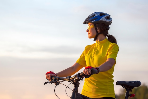 Schöne und glückliche radfahrerin mit einem fahrrad auf