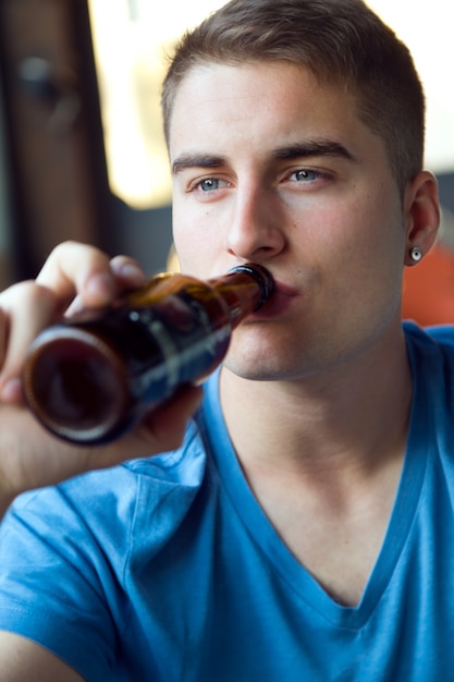 Schöner junger mann trinkt bier in der bar. Kostenlose Foto