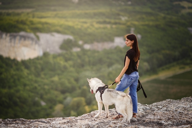 Schönes mädchen spielt mit einem hund, grauer und weißer husky, in den