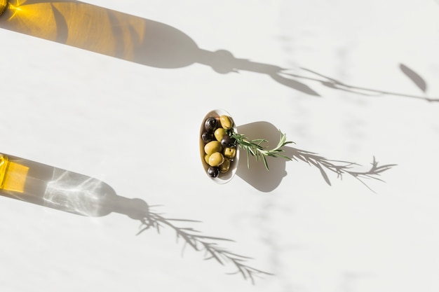 Schüssel oliven mit schatten der ölflasche auf weißem ...
