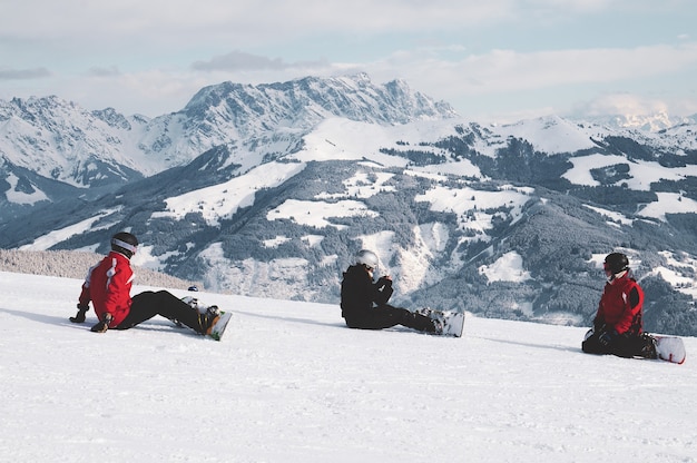 Schuss Von Snowboardern Die Auf Schnee Sitzen Und Die Weissen Berge In Tirol Osterreich Betrachten Kostenlose Foto