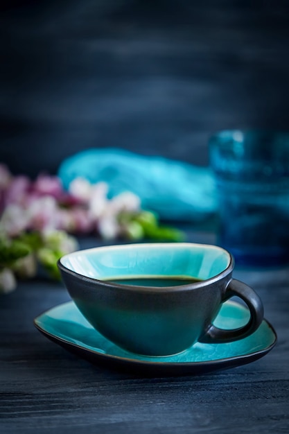 Schwarzer Kaffee In Einer Turkisfarbenen Tasse Und Blumen Auf Einem Schwarzen Holzernen Hintergrund Premium Foto