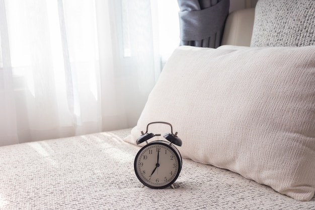 Schwarzer wecker auf weißem bett im wohnzimmer. Premium Fotos