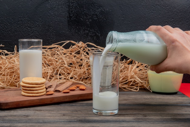 Seitenansicht der hand, die milch von der flasche in glas