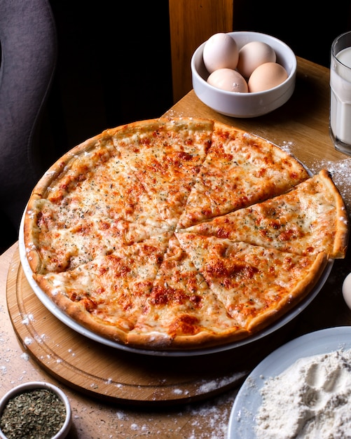 Seitenansicht der Käsepizza mit Tomaten und Gewürzen