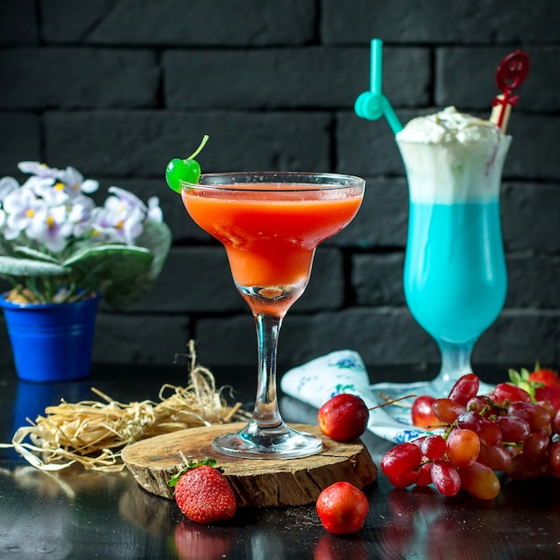 Seitenansicht des roten cocktails im glas mit frischen früchten auf ...