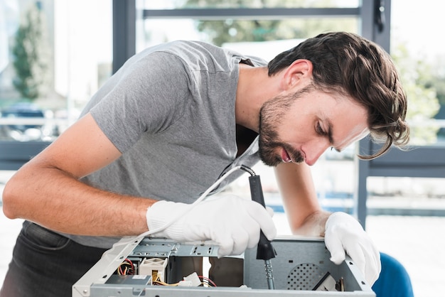Seitenansicht eines jungen männlichen technikers, der an defektem computer arbeitet Kostenlose Fotos