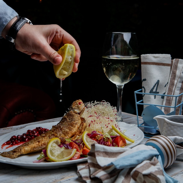 Seitenansicht gebratener fisch mit glas wein und zitrone