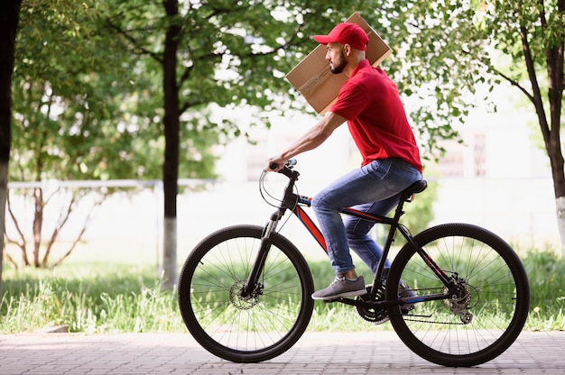Seitenansicht junger mann, der paket auf einem fahrrad
