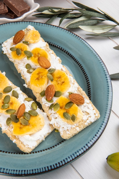Seitenansicht von knusprigen crackern mit frischkäse, bananen-, mandel ...