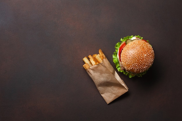 Selbst gemachter hamburger mit bestandteilrindfleisch, tomaten, kopfsalat, käse, zwiebel, gurken und pommes-frites auf rostigem hintergrund Premium Fotos
