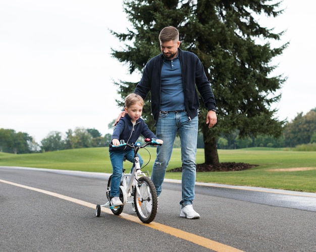 Sohn fährt mit dem fahrrad im park neben seinem vater