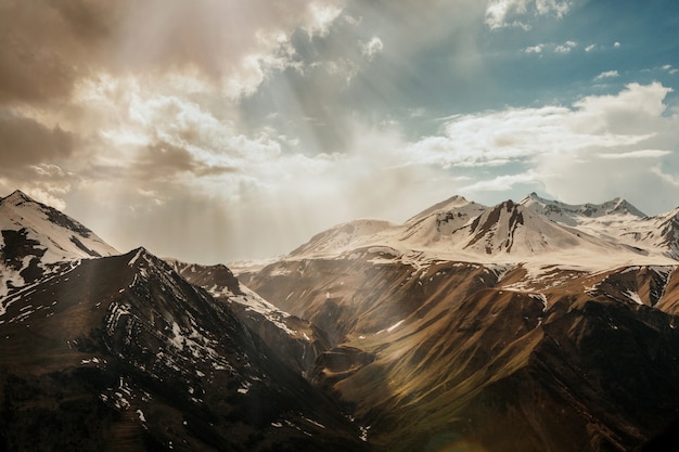 Sonnenstrahlen Dringen Durch Die Wolken In Das Verschneite Hochgebirge Kostenlose Foto