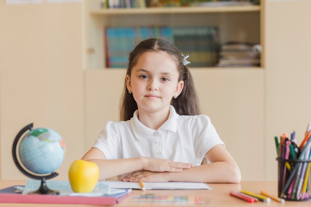 Sorgfältiger schüler, der am schreibtisch sitzt Kostenlose Fotos