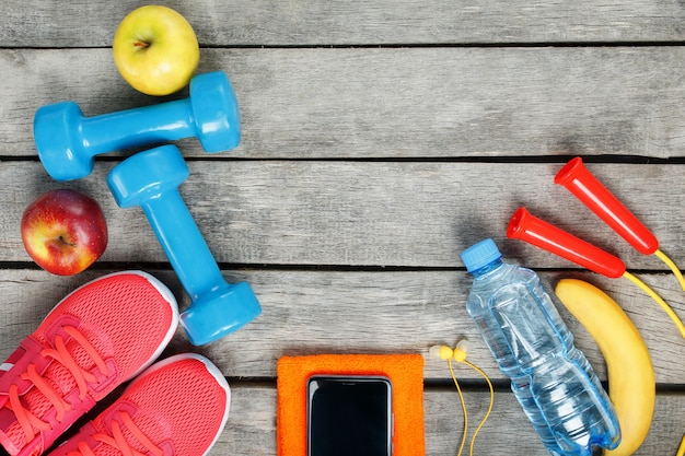 Sportausrüstung und der smartphone mit kopfhörern auf einem hölzernen Premium Fotos