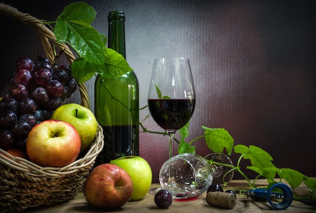 Stillleben mit flasche und glas rotwein, äpfel und trauben. | Premium-Foto