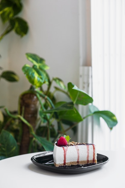 Süßer käsekuchen mit frischer beere auf schwarzer keramischer platte ...